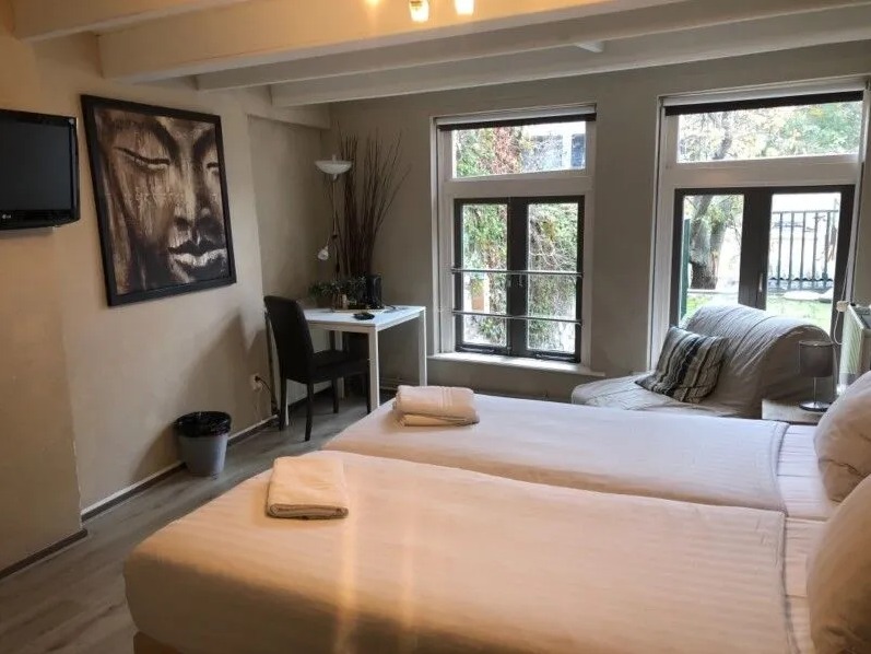 Slaapkamer met dubbele bedden en grote ramen